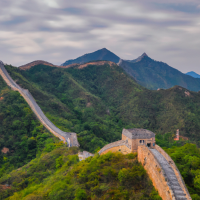 A panoramic view of the Great Wall winding through mountainous terrain, dotted with ancient watchtowers, capturing the majesty and scale of this iconic structure.