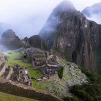 The ancient city of Machu Picchu shrouded in morning mist, with terraced fields and mountain peaks surrounding it, highlighting the Incan architectural mastery.